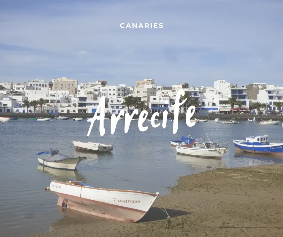 White boat beached in front of the white houses of Arrecife