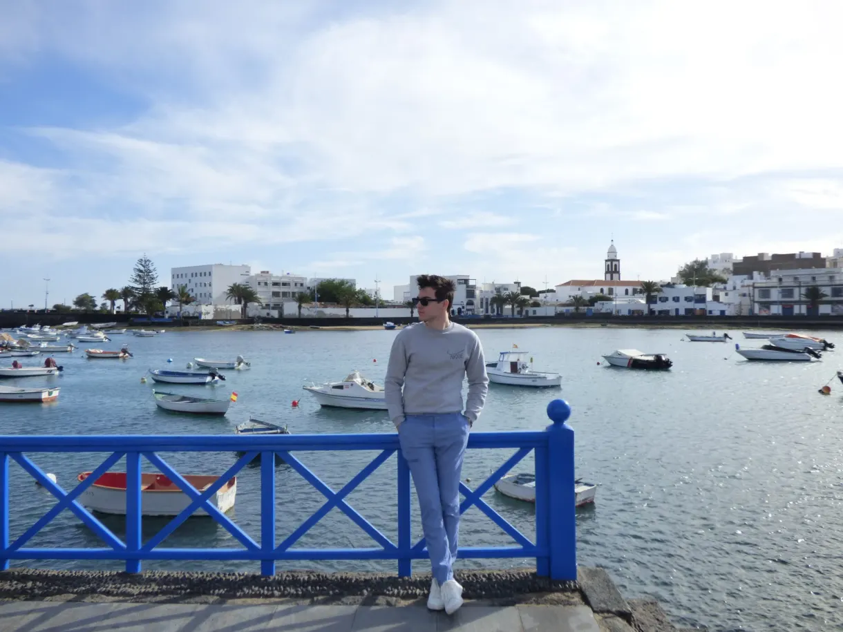 Traveller leaning against the blue railing facing the boats