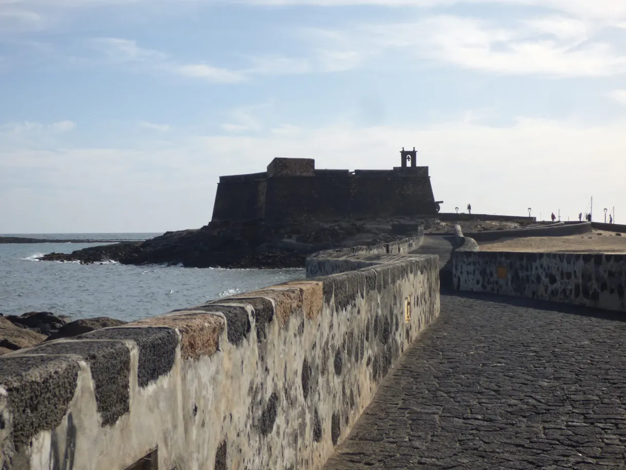 Low volcanic stone wall in front of the fort at the water's edge