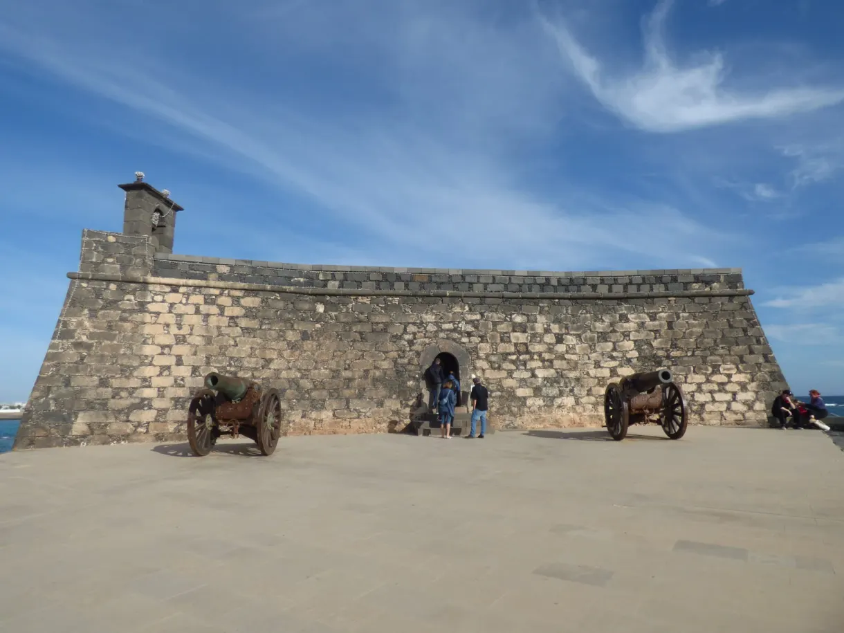 Two old cannons in front of the stone ramparts of the fort