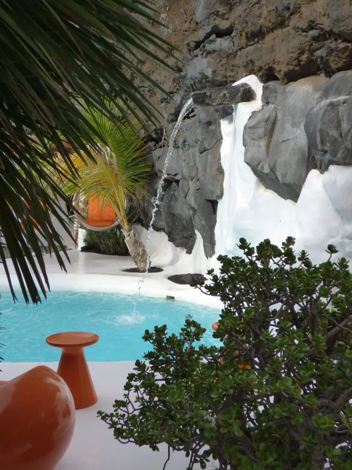 Orange jars and turquoise pool beneath the palm fronds