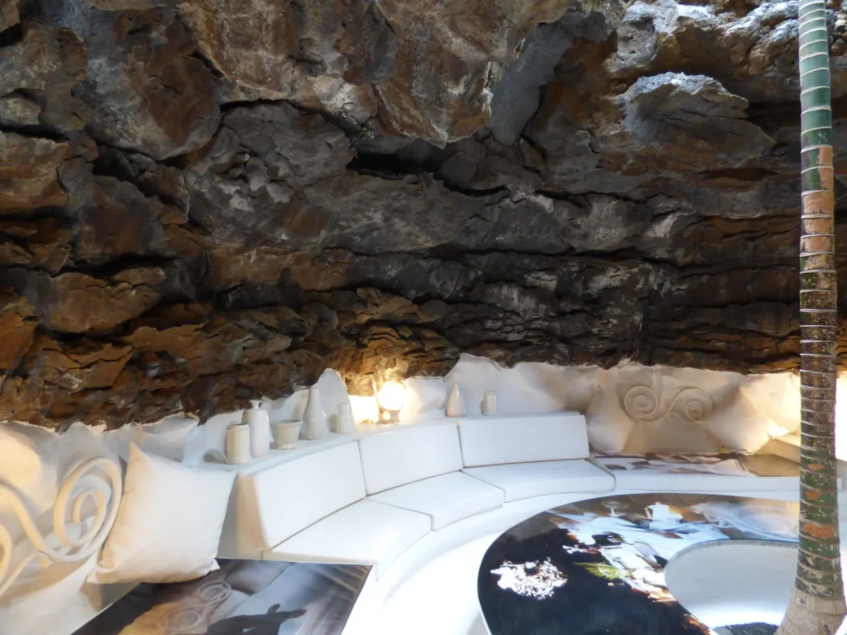 Curved white lounge beneath a vault of volcanic rock