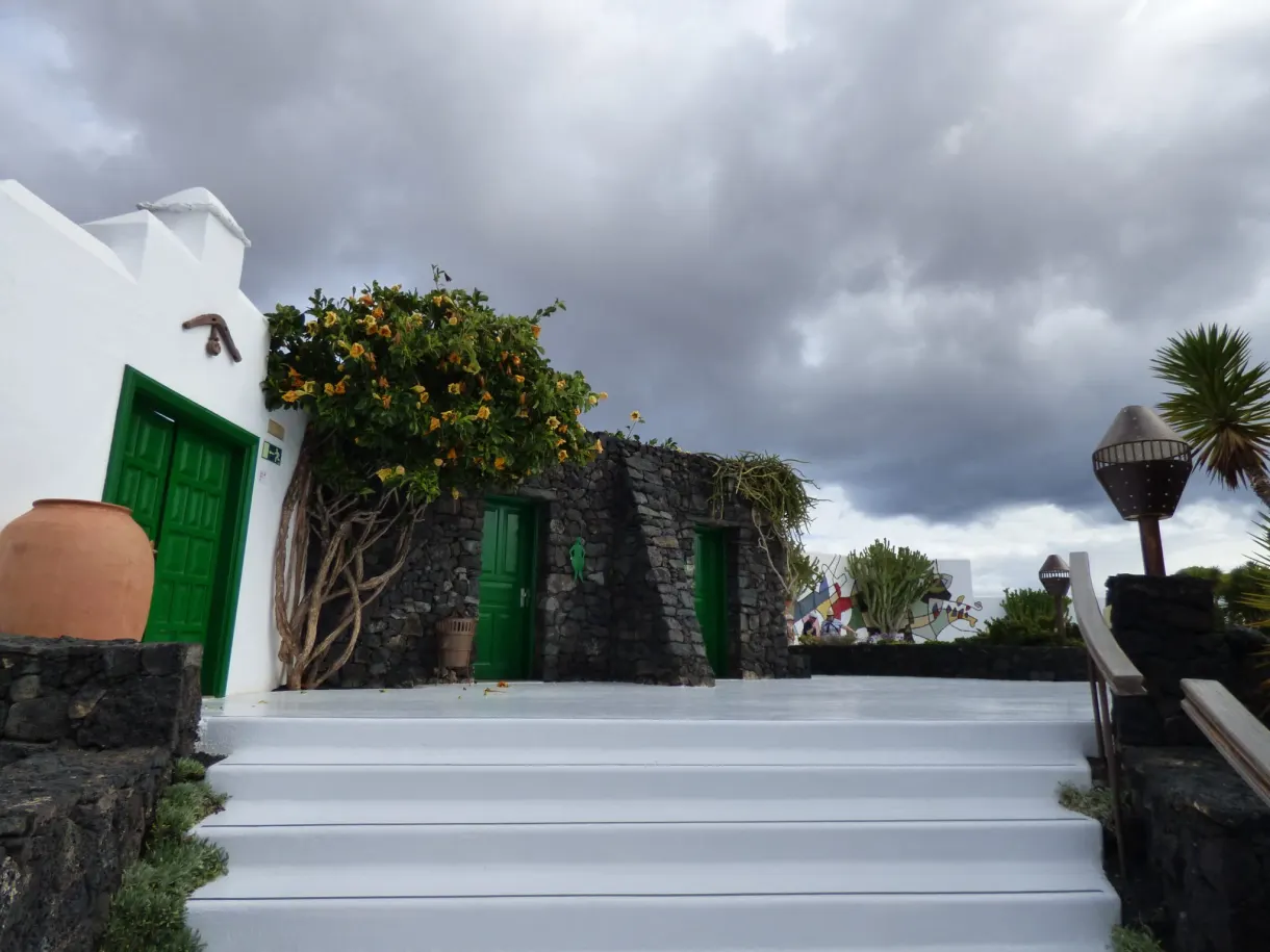 White staircase between whitewashed walls and green doors