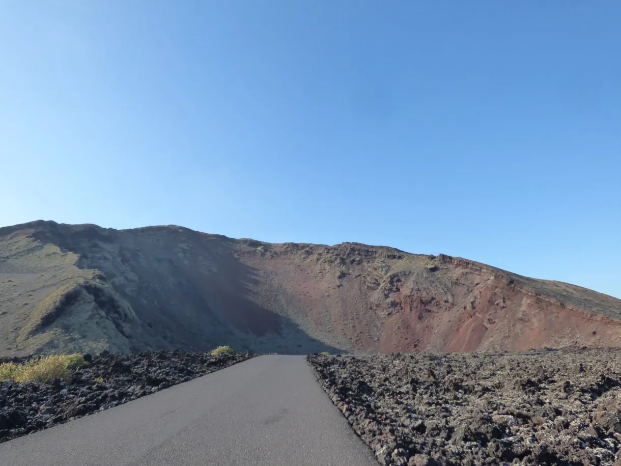 Route asphaltée traversant un cratère sombre du Timanfaya