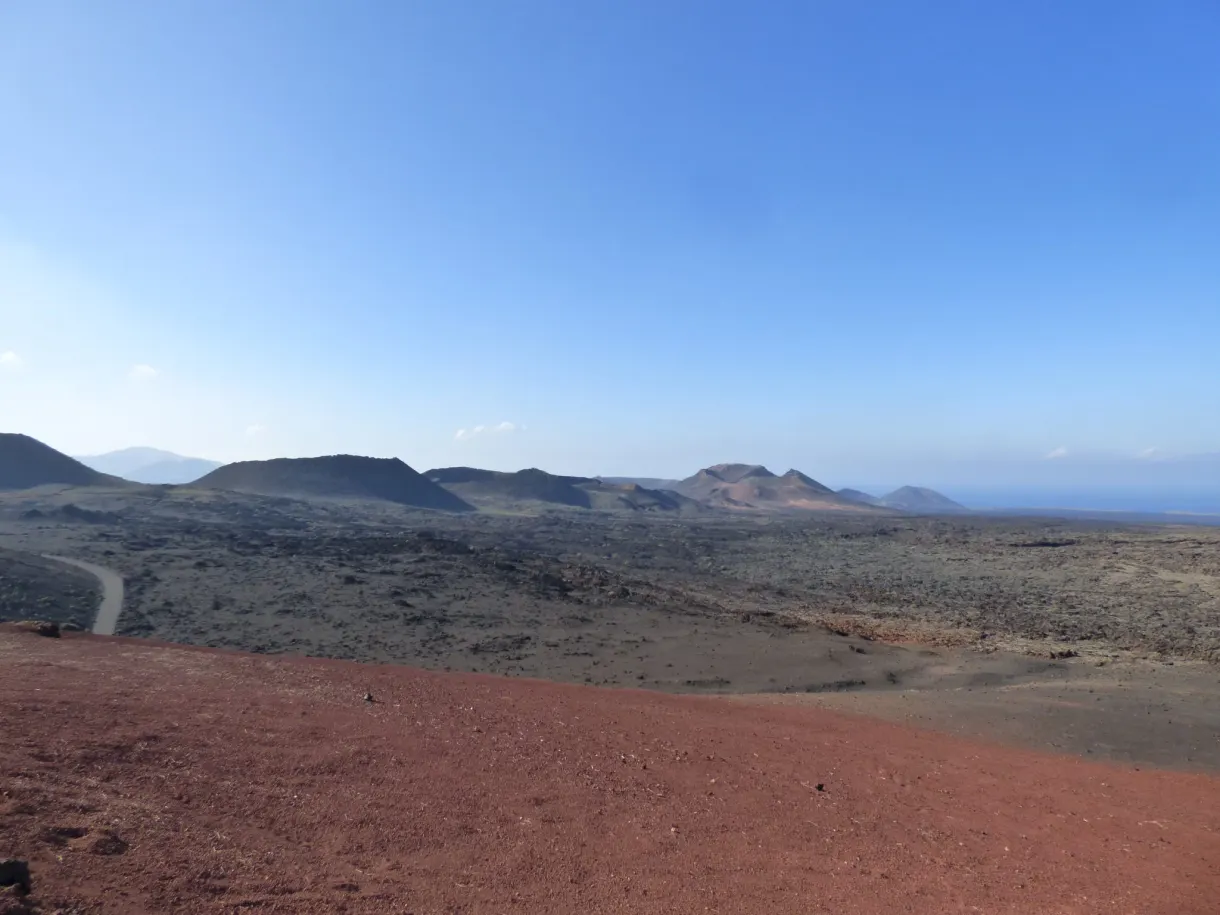 Plaine de lapilli rouge et cônes volcaniques à l'horizon