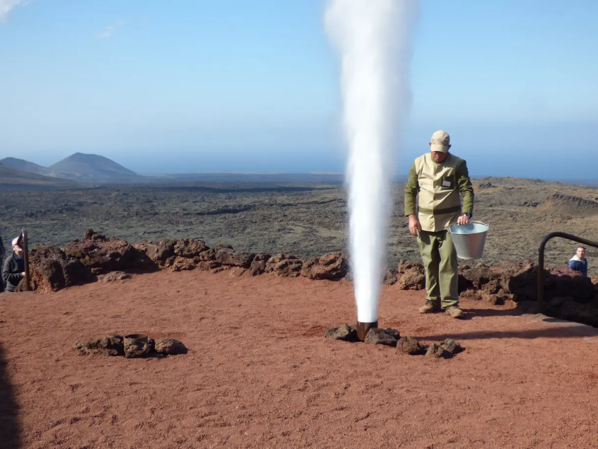 Guide déclenchant un geyser d'eau au-dessus du sol brûlant