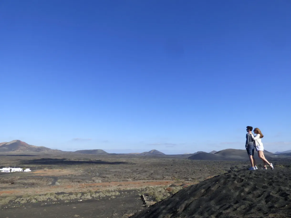 Couple au bord d'une pente noire face au panorama de l'île