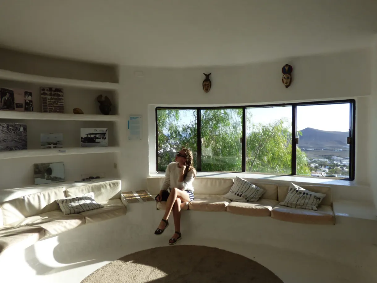 Femme assise sur la banquette blanche devant la baie vitrée