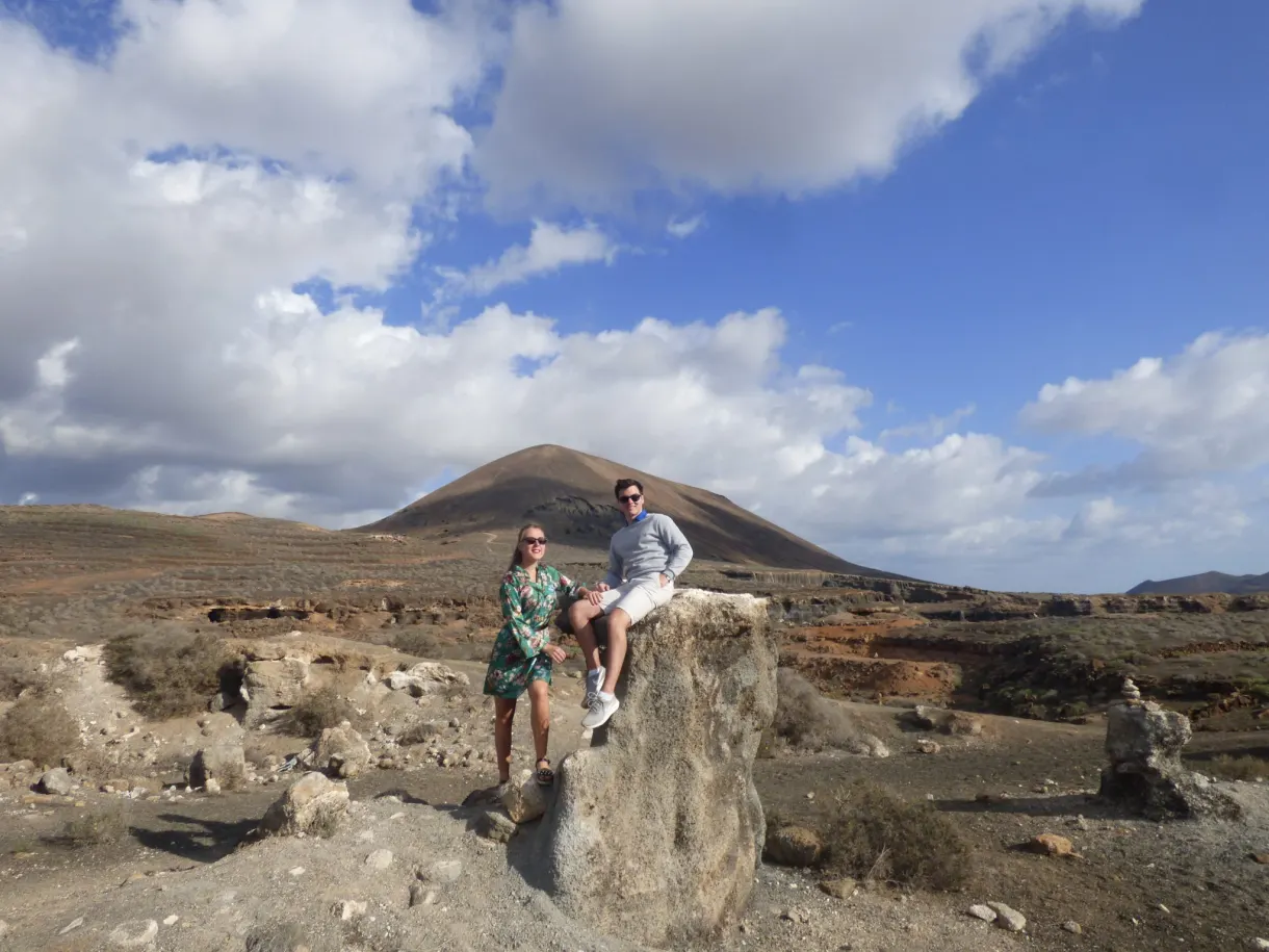 Couple assis sur un bloc de pierre face au volcan