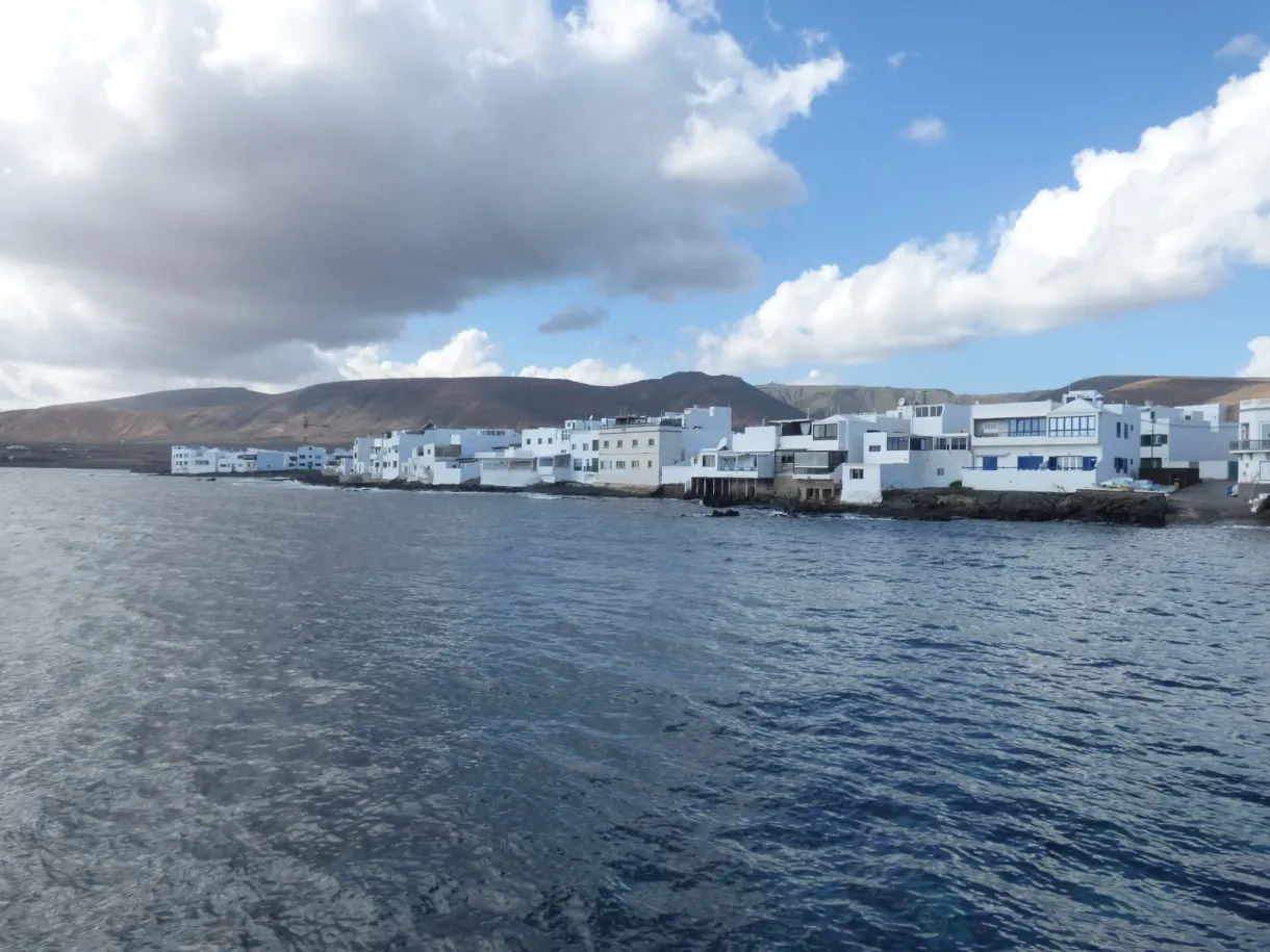 Village blanc étiré au ras de l'eau sous un ciel nuageux