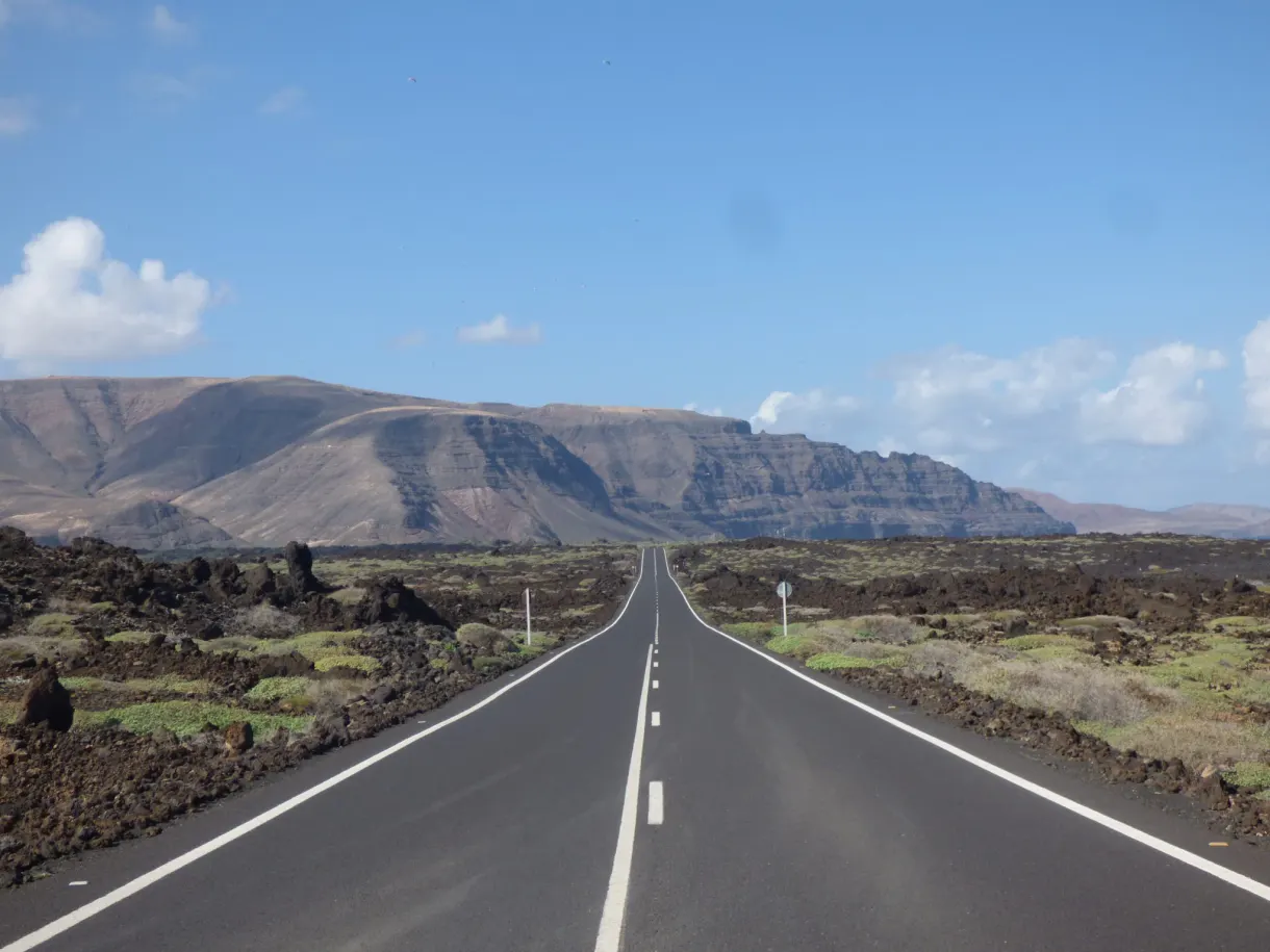 Route droite pointant vers le massif brun du nord