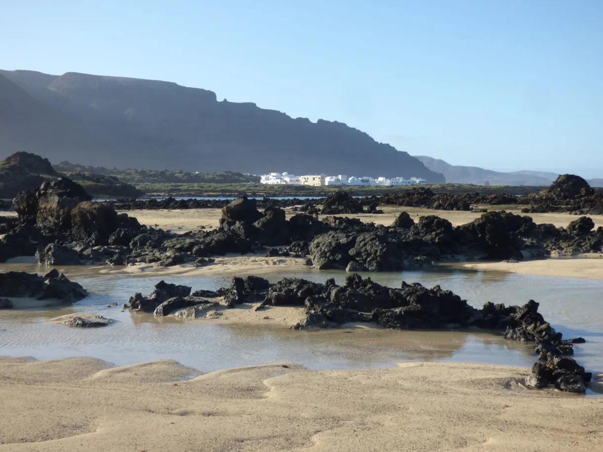 Rochers noirs affleurant dans une eau basse devant la falaise