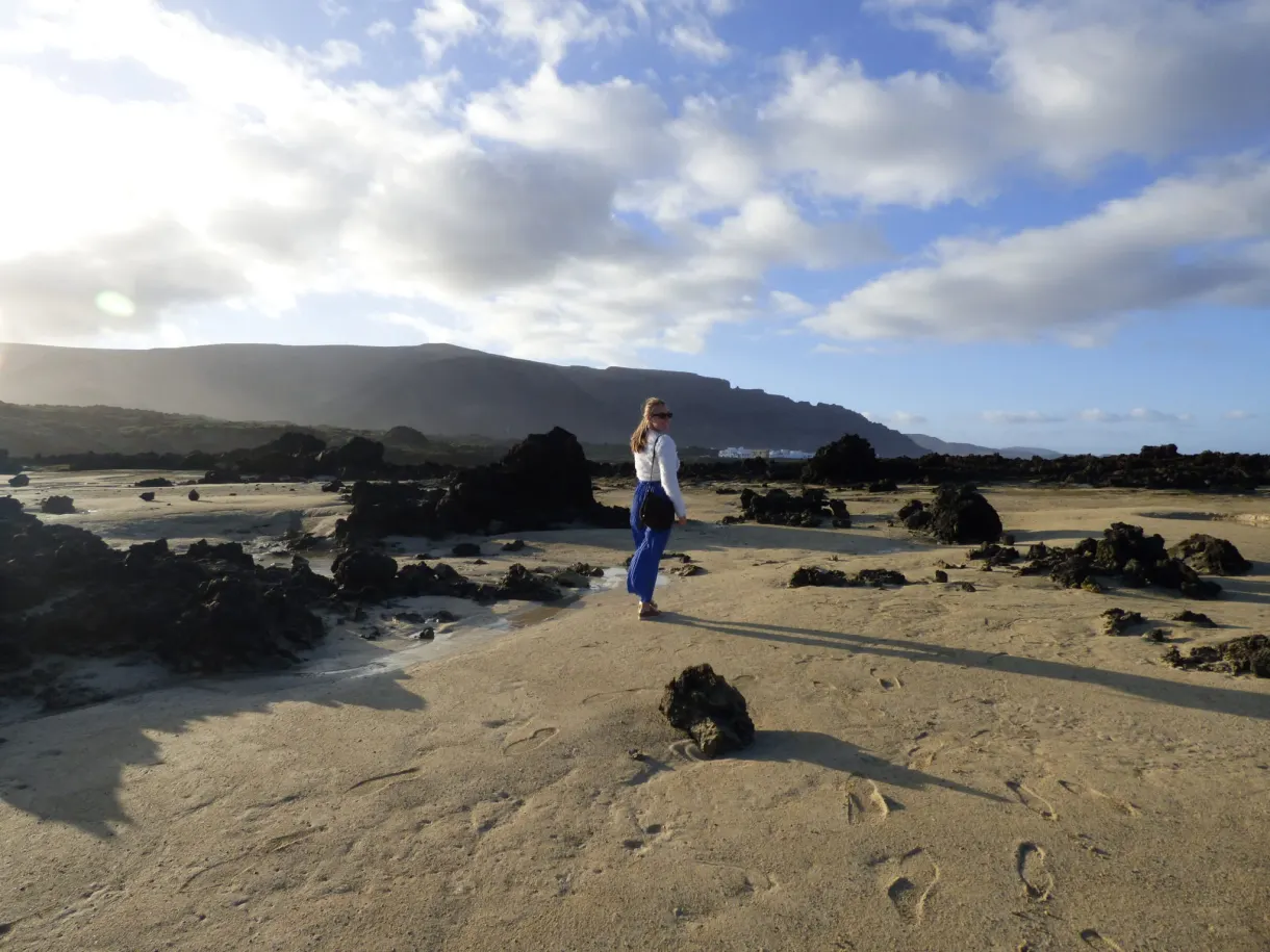 Femme debout sur le sable clair parmi les blocs de lave