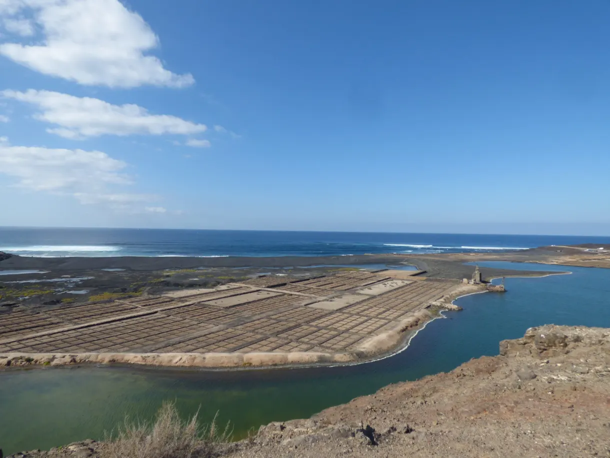 Salines beiges séparant le lagon de l'océan sous un ciel limpide