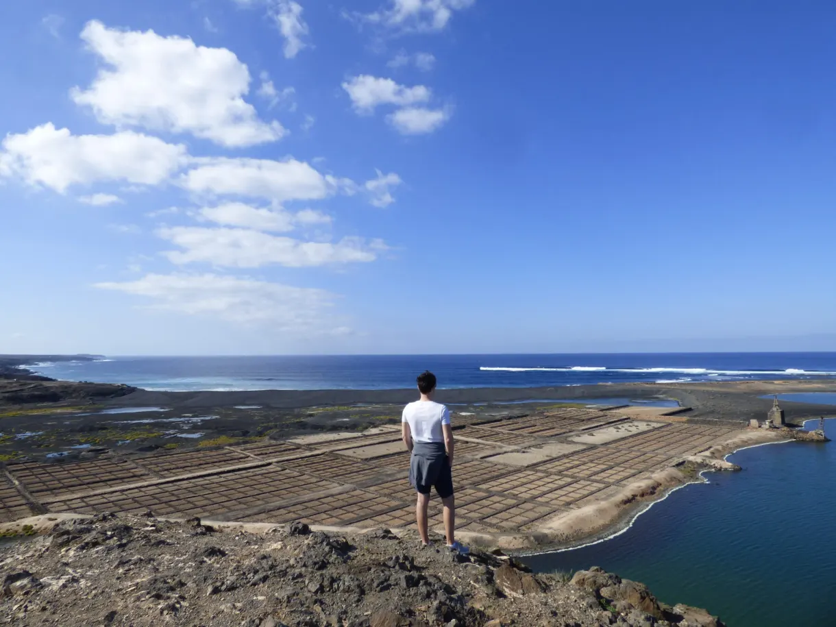 Homme seul debout sur une butte de lave face aux salines