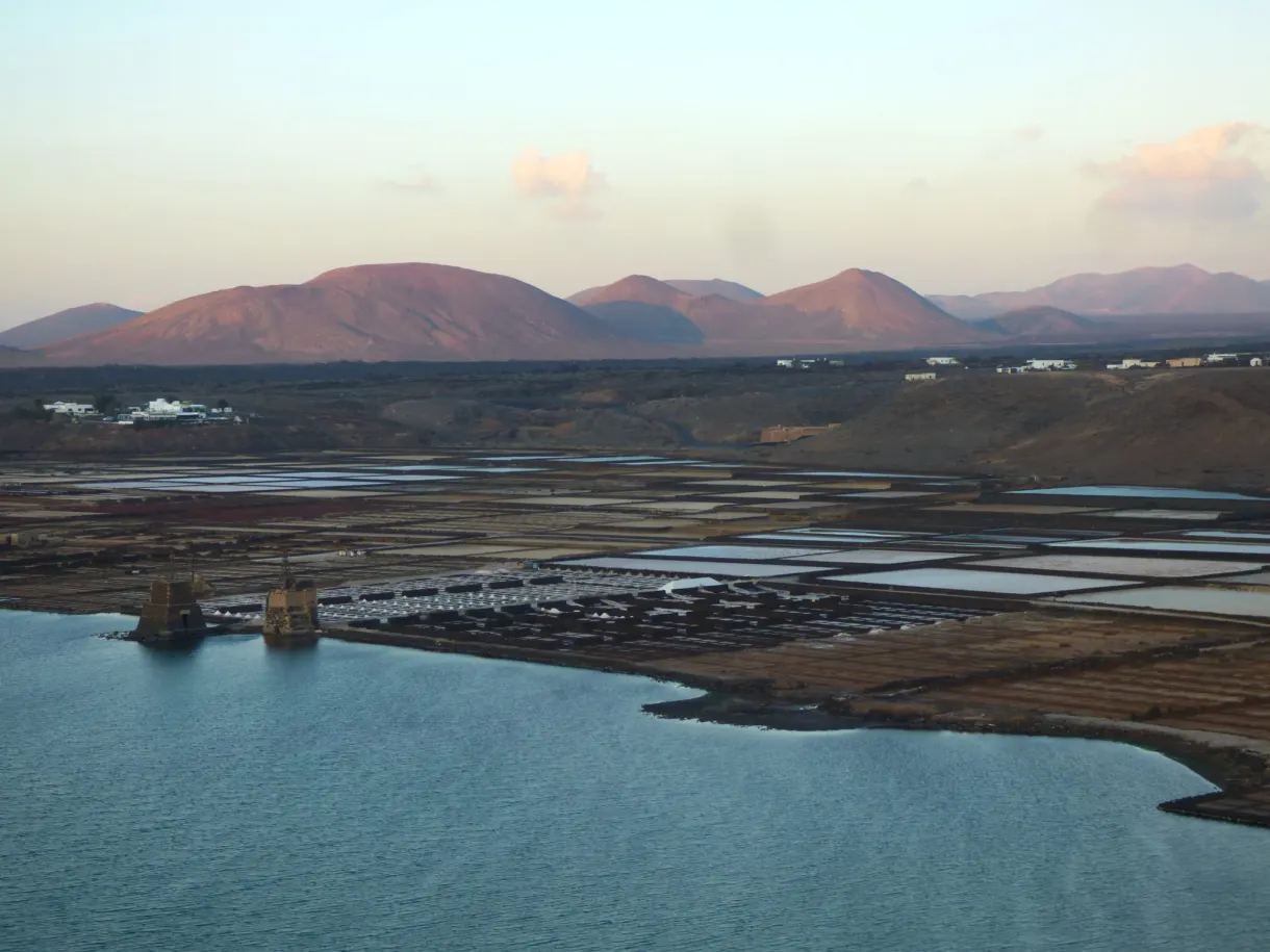 Lumière rasante sur les salines et les cônes rouges du fond