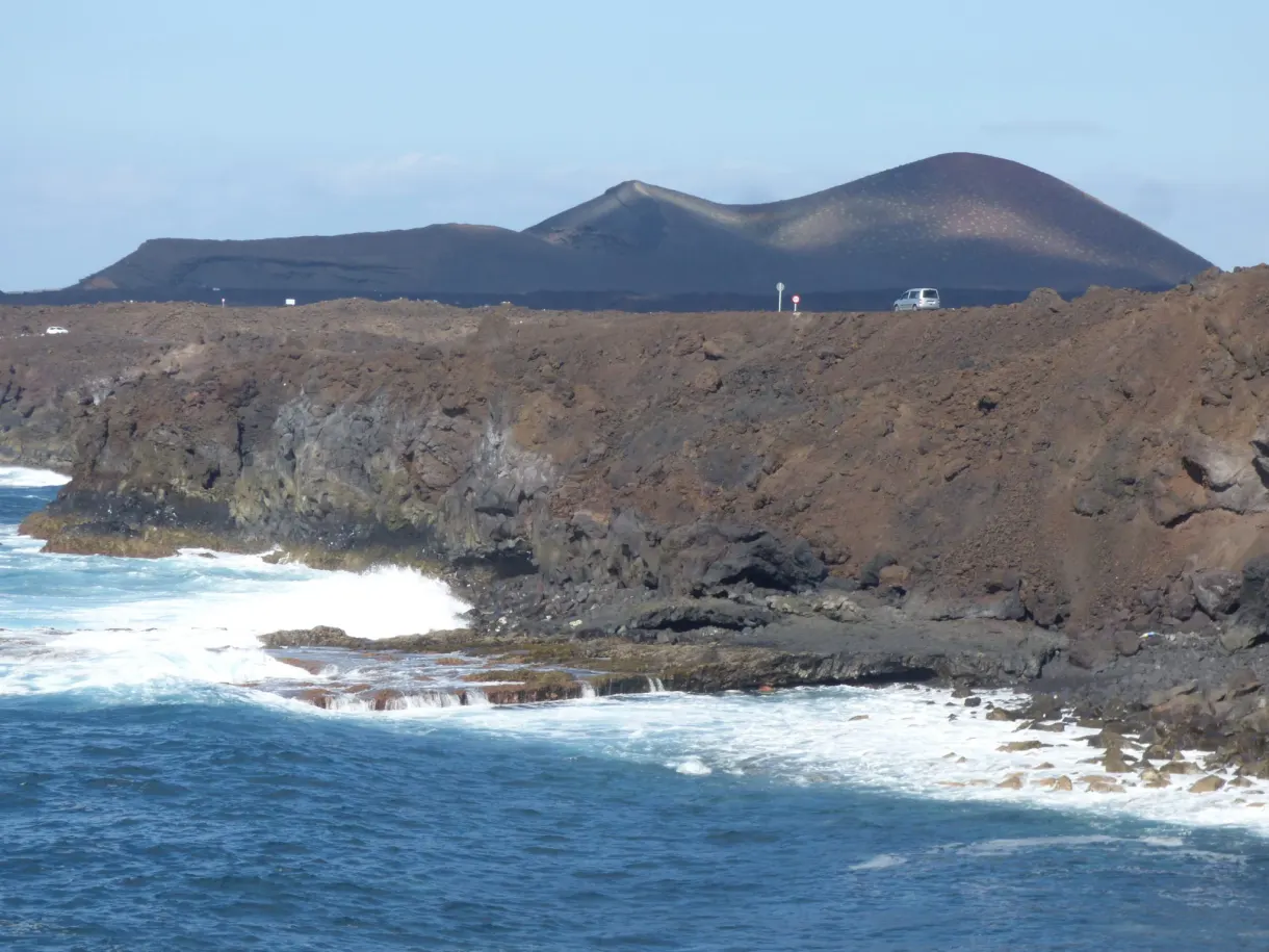 Falaises noires et écume blanche au pied d'un volcan