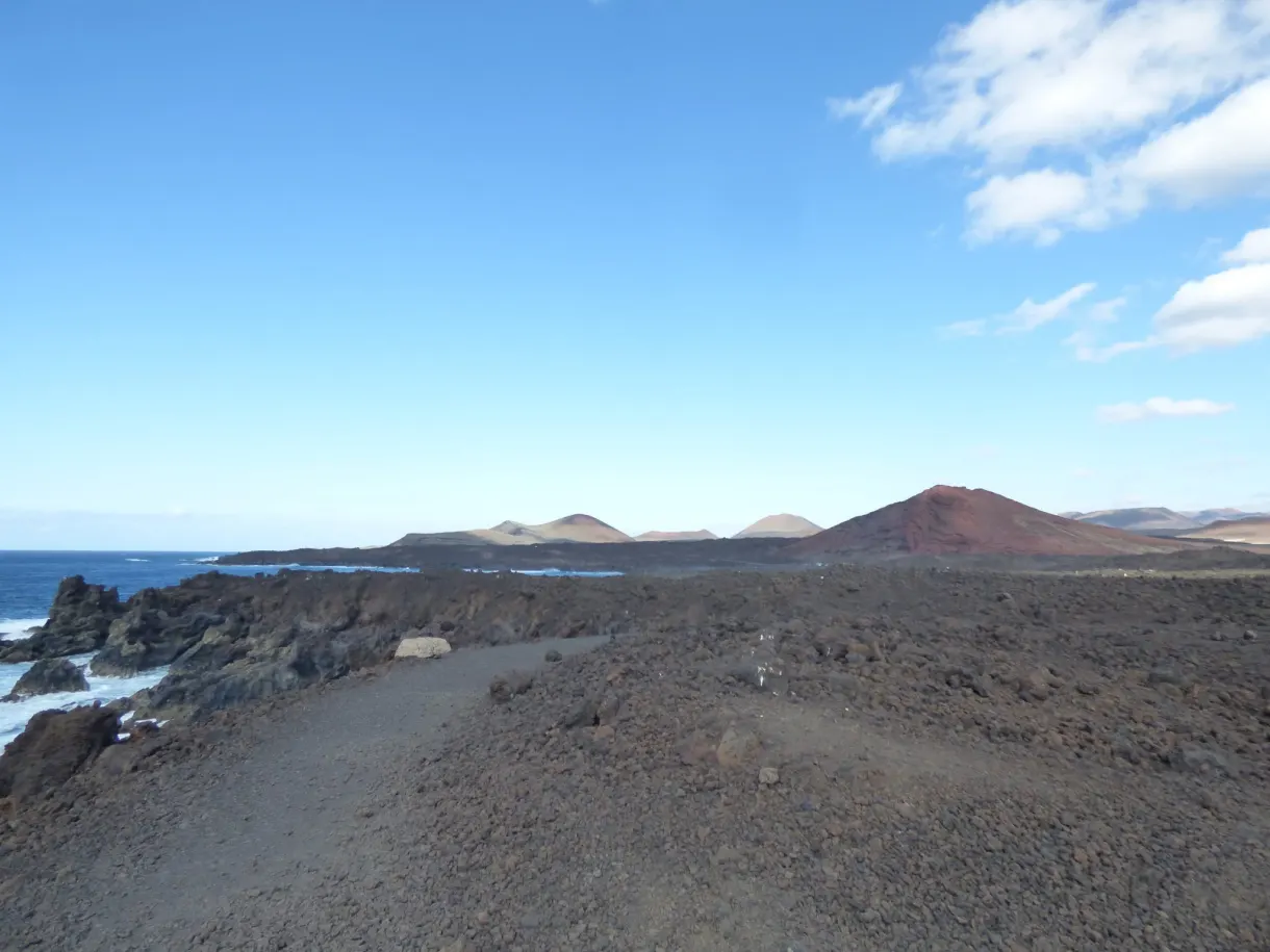 Chemin de graviers noirs vers la mer et les cônes volcaniques