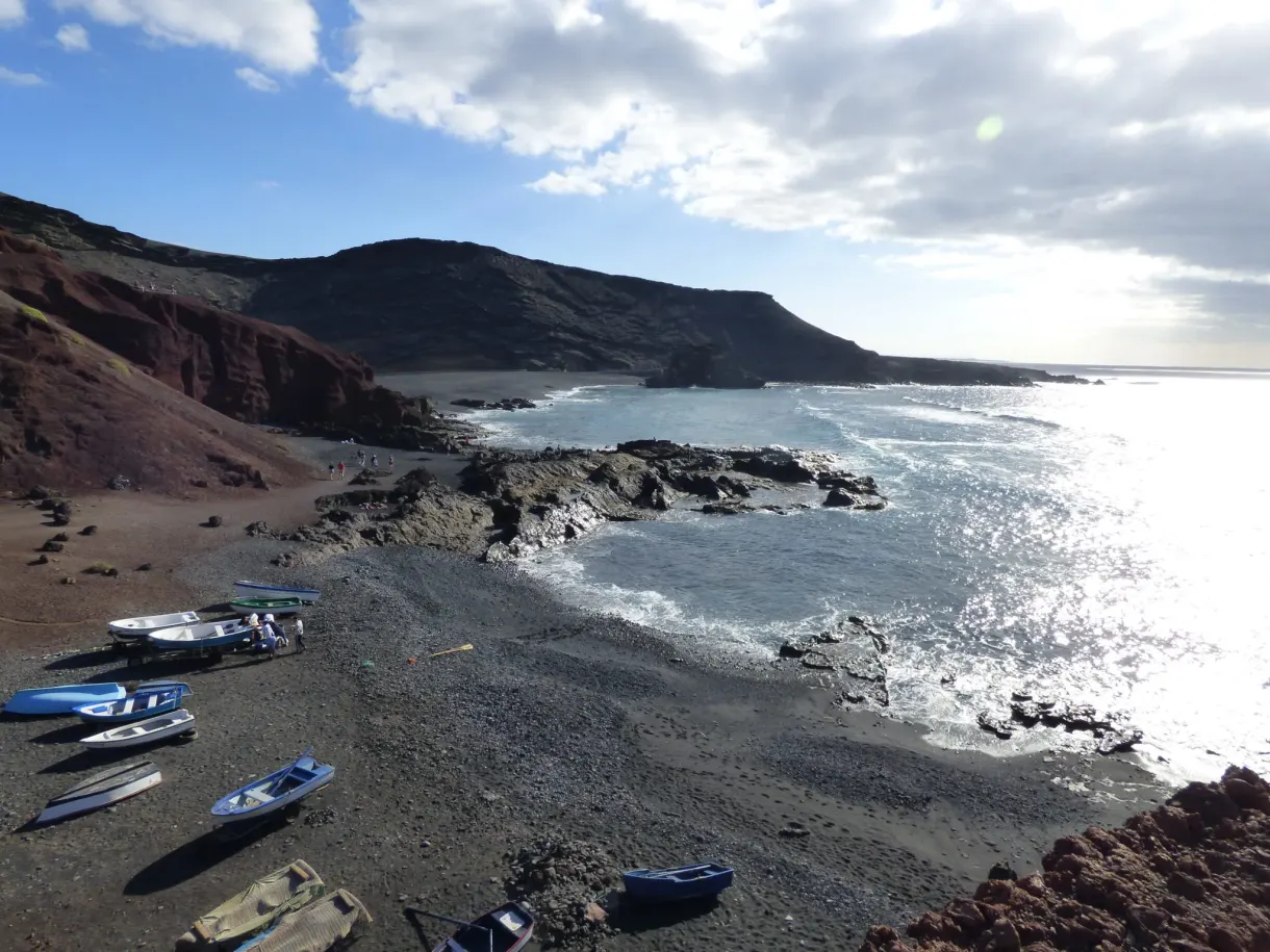 Barques de pêche échouées sur le sable noir du village