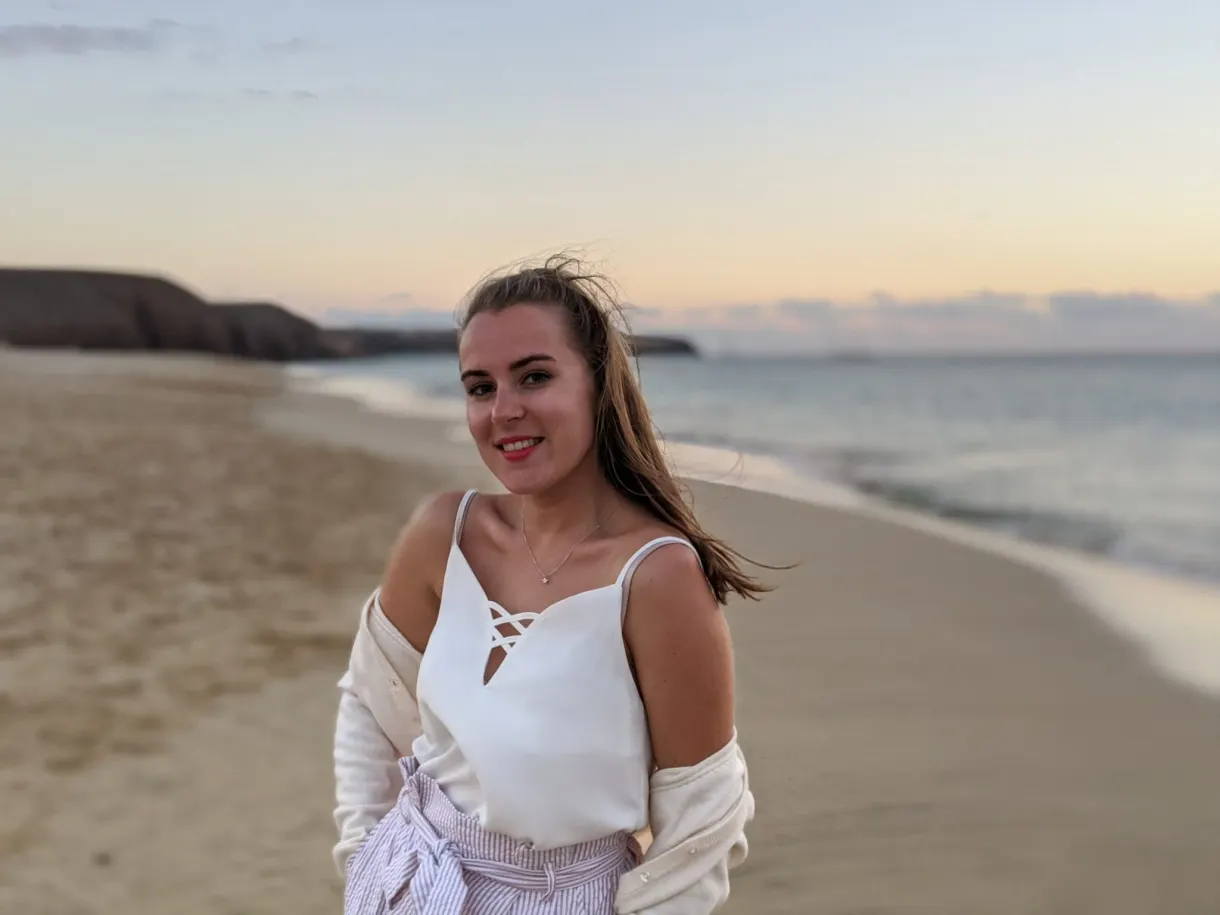 Jeune femme souriante sur la plage dans la lumière du soir