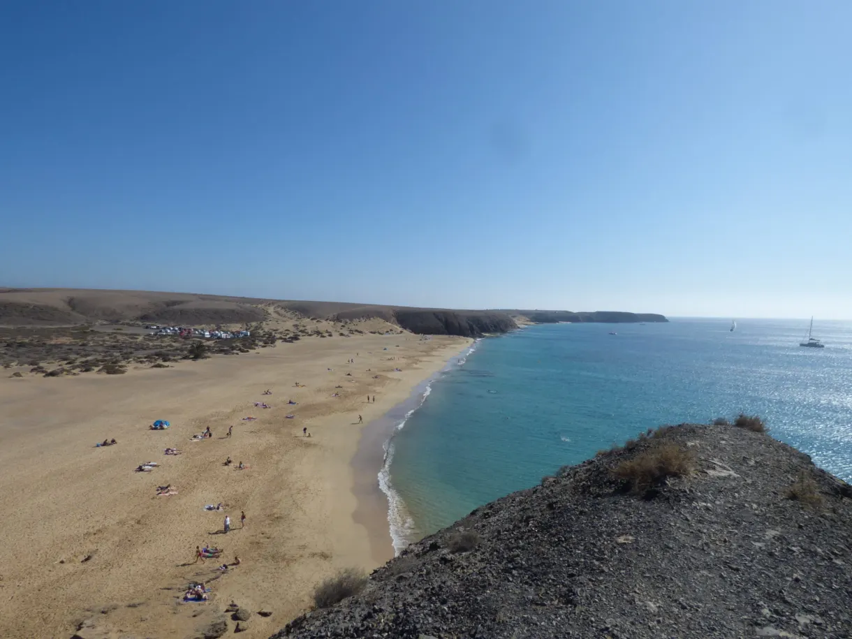 Baie ourlée de sable et voiliers au large
