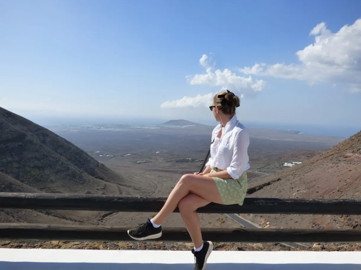 Femme assise sur un muret face à la vallée