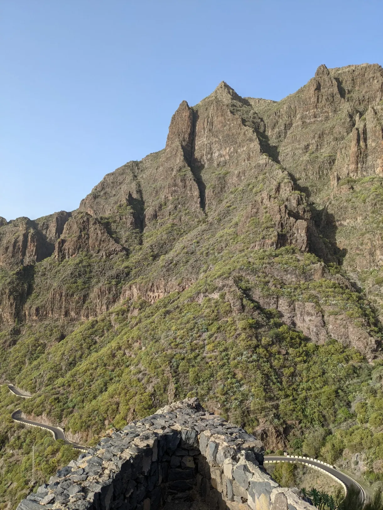Piton rocheux acéré dominant une route en lacets