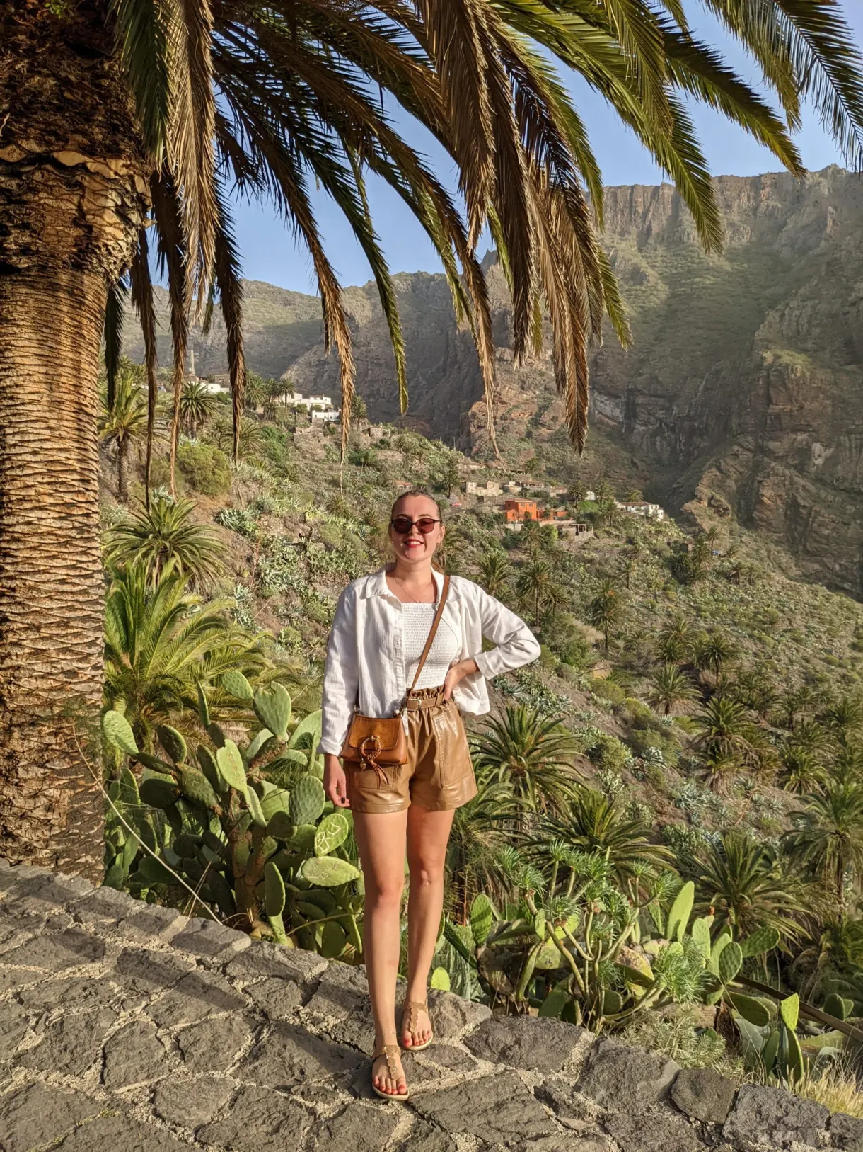 Femme sur un escalier pavé entre palmiers et agaves
