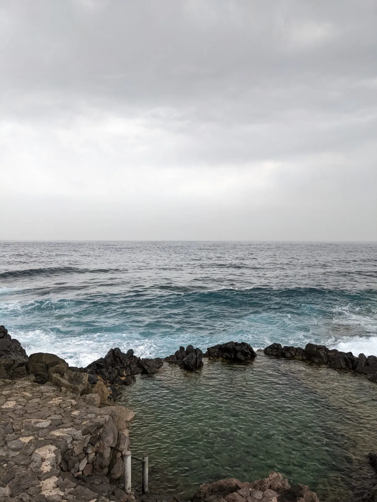 Piscine naturelle creusée dans la roche volcanique face à l'océan