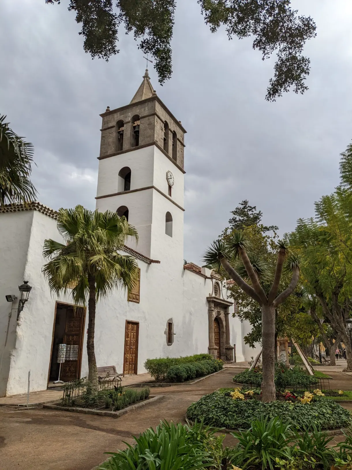 Église blanche et son clocher au-dessus d'un jardin fleuri