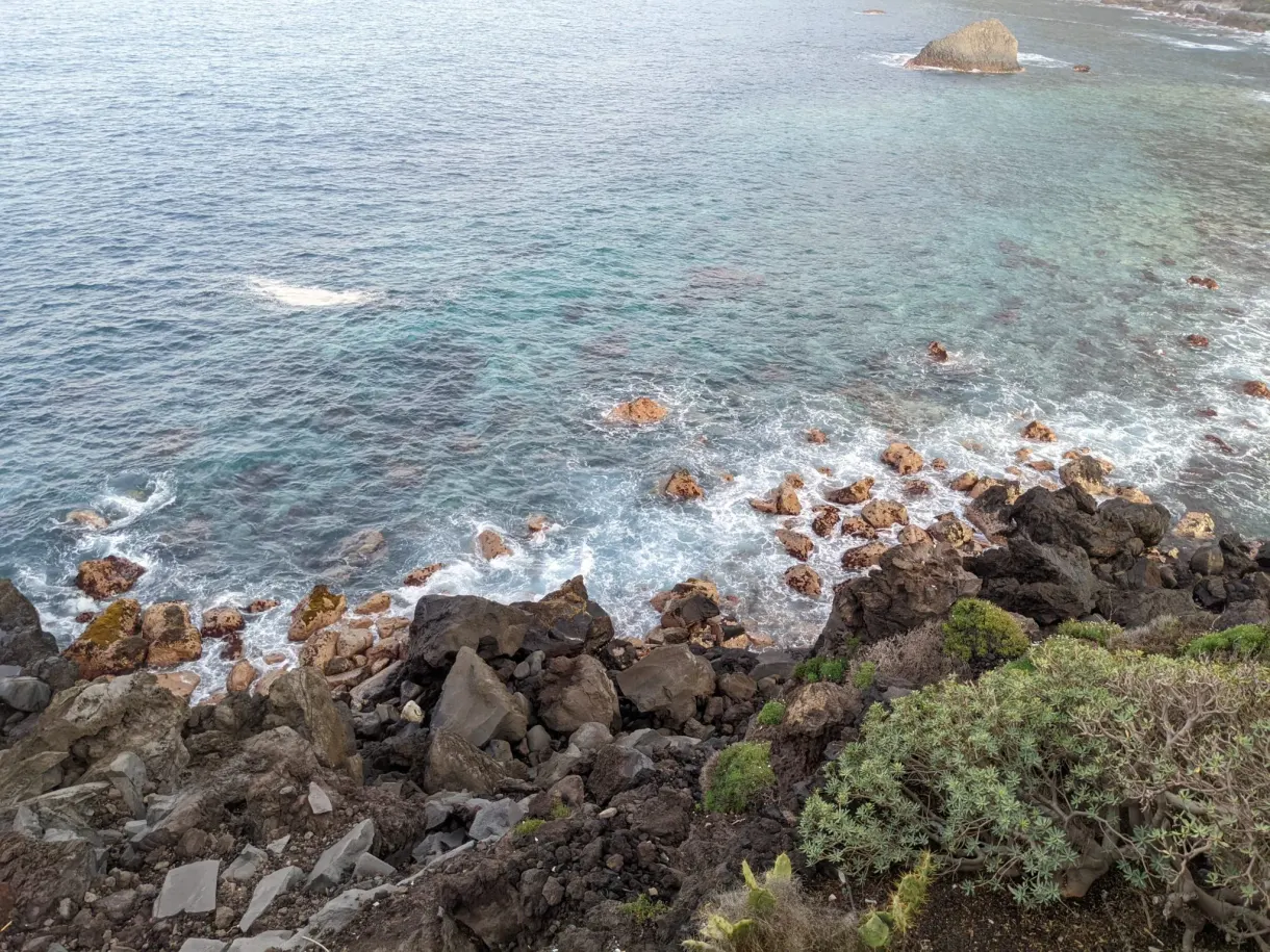 Eau turquoise et rouleaux d'écume vus depuis la falaise