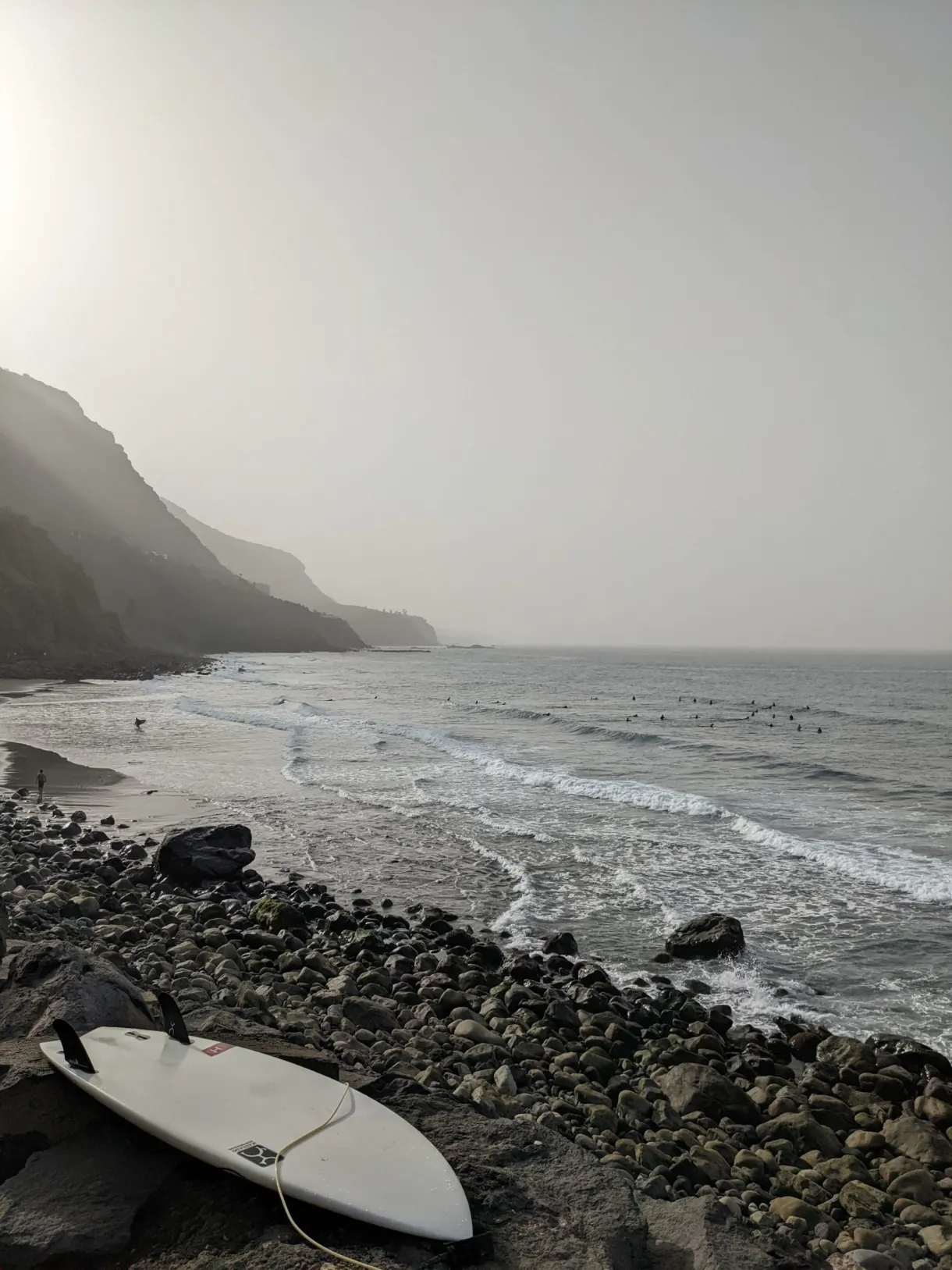 Planche de surf posée sur une plage de galets noirs