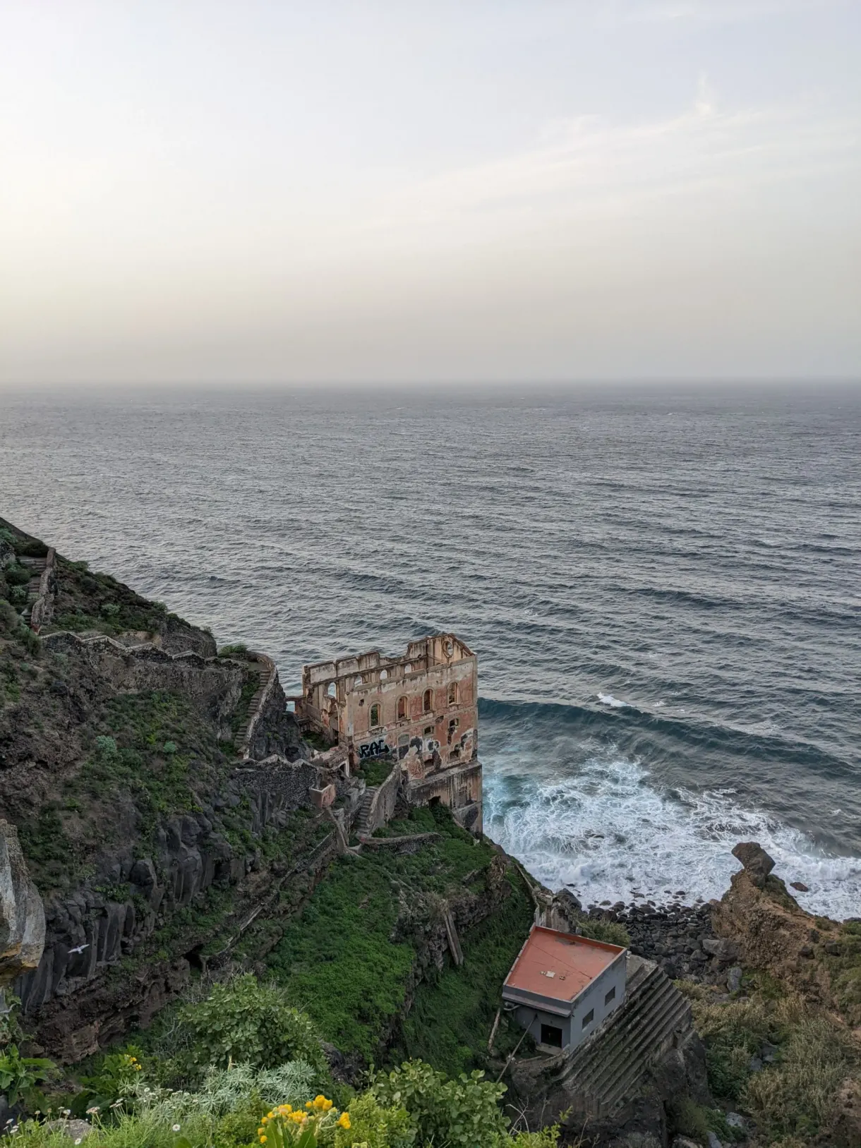 Bâtisse ocre en ruine accrochée au-dessus des vagues