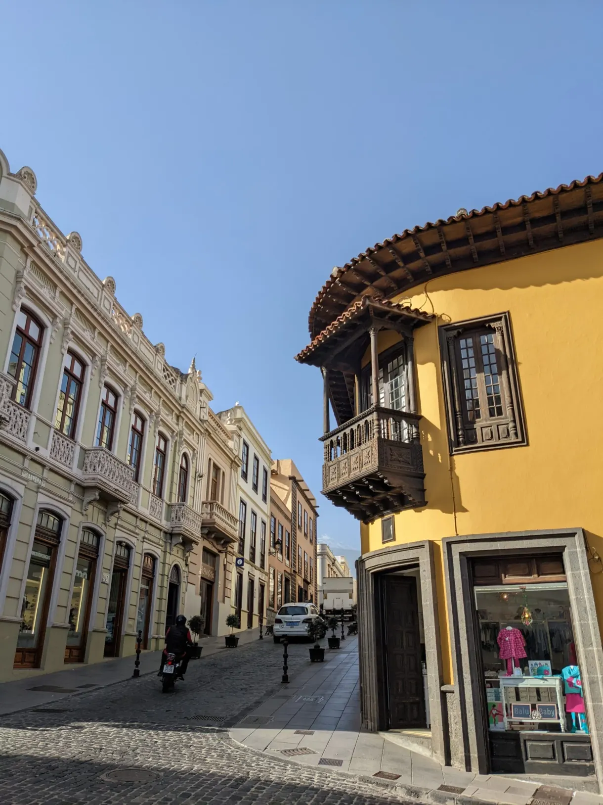 Rue en pente et balcons de bois d'une maison jaune