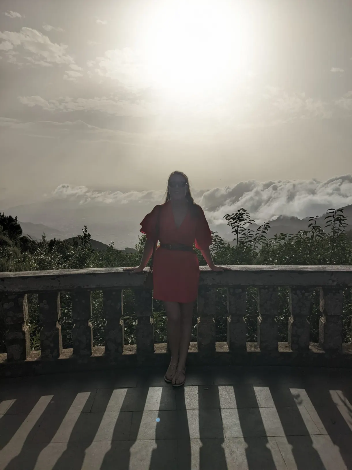 Femme en robe rouge face à une mer de nuages