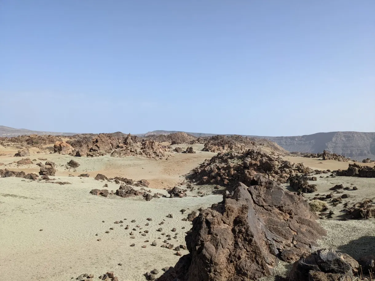 Scattered blocks of lava on the pale sand of the caldera