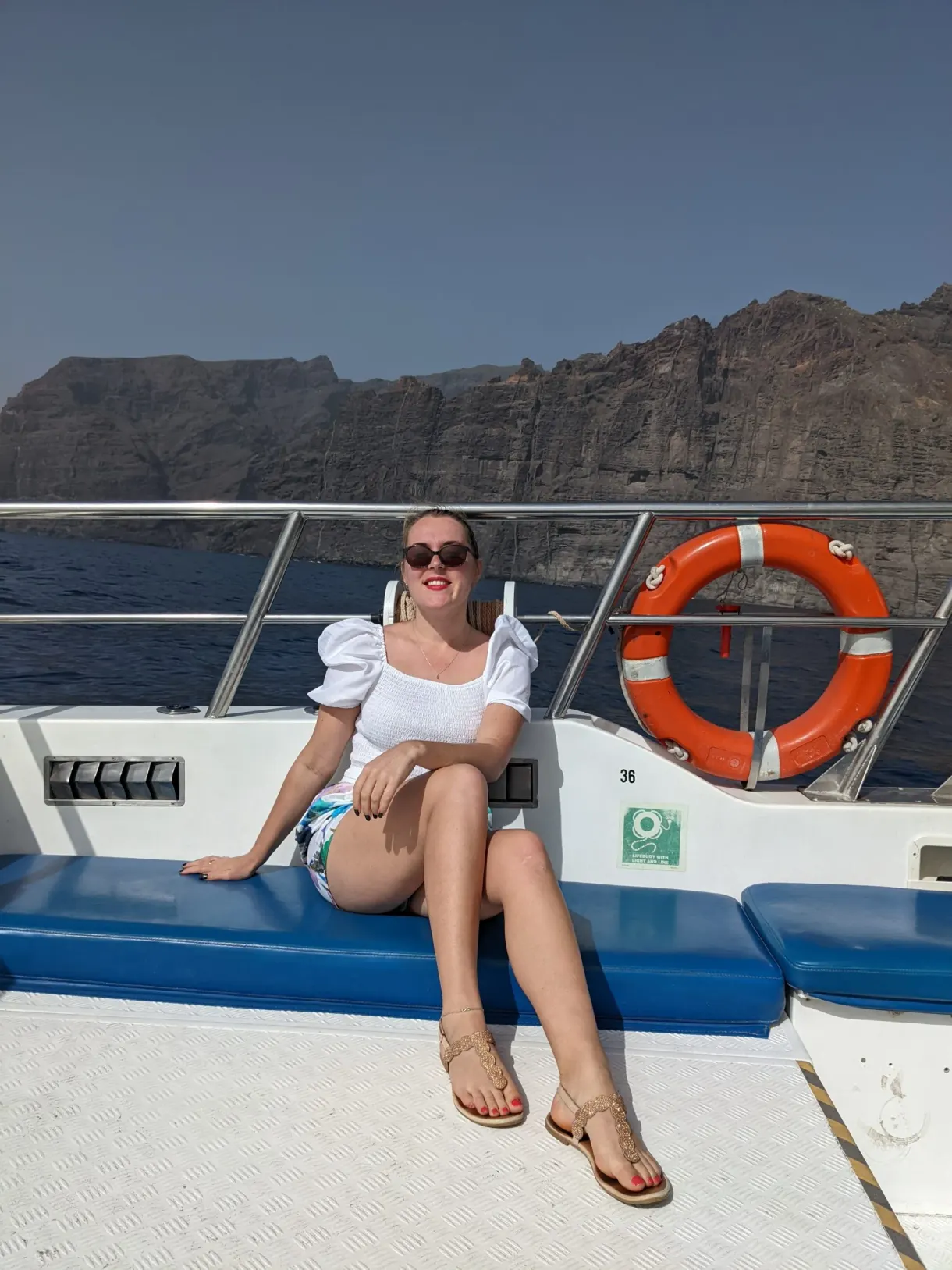 Femme assise sur le pont du bateau près d'une bouée orange