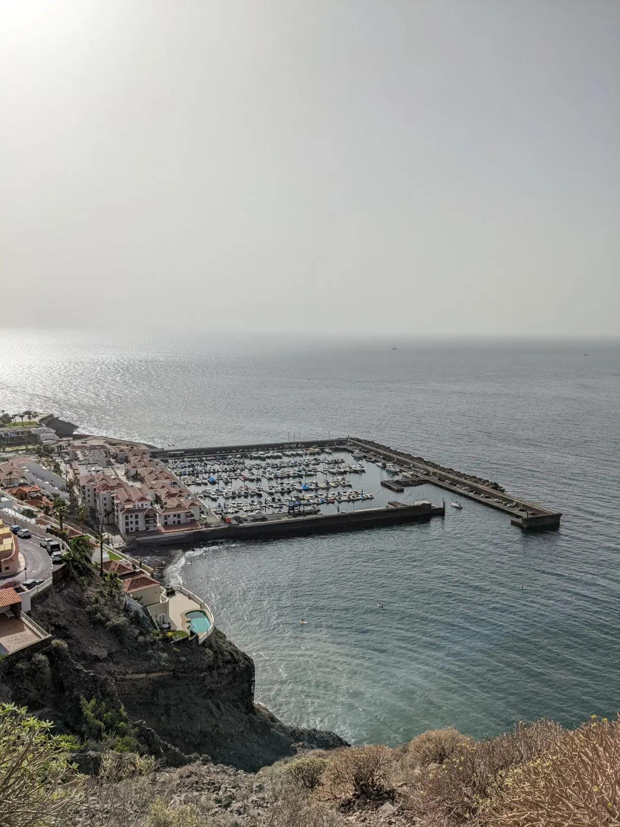 Port de plaisance blotti au pied de la falaise dans la brume