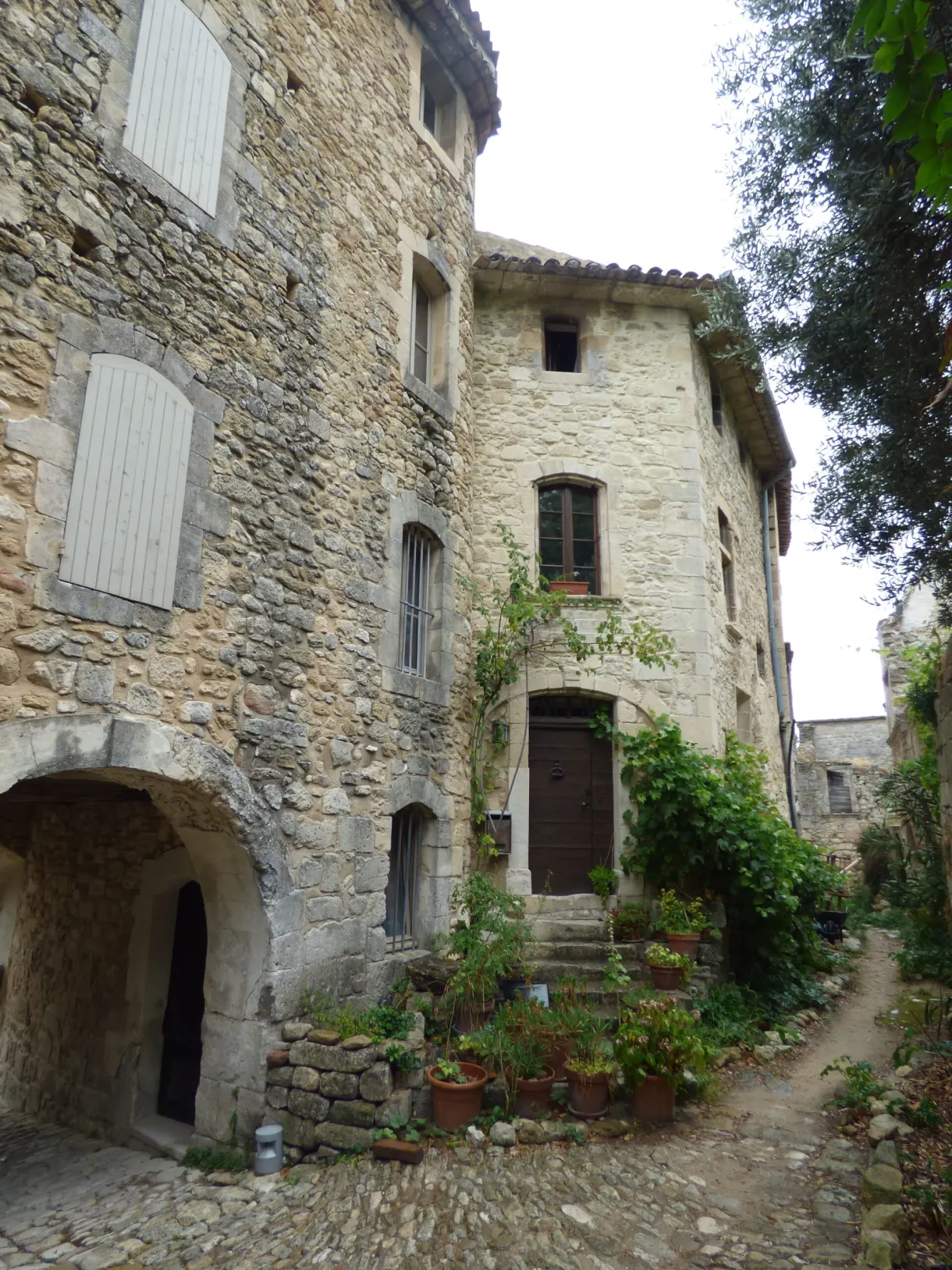 Maison de pierre à porche voûté et pots de fleurs