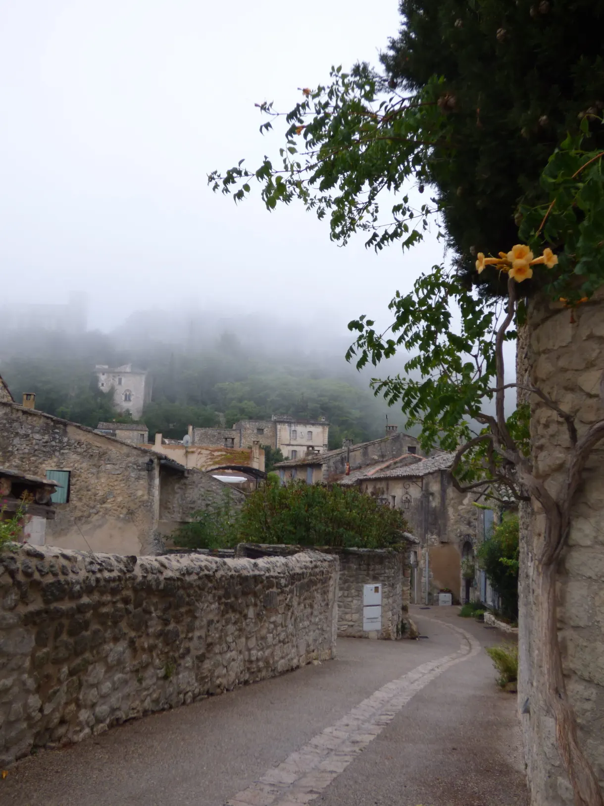 Ruelle de village enveloppée de brume le long d'un mur de pierre