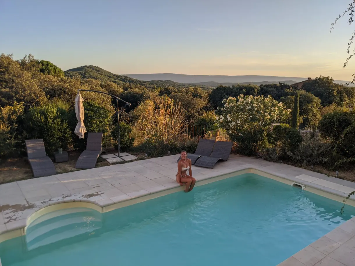 Femme assise au bord de la piscine au soleil couchant