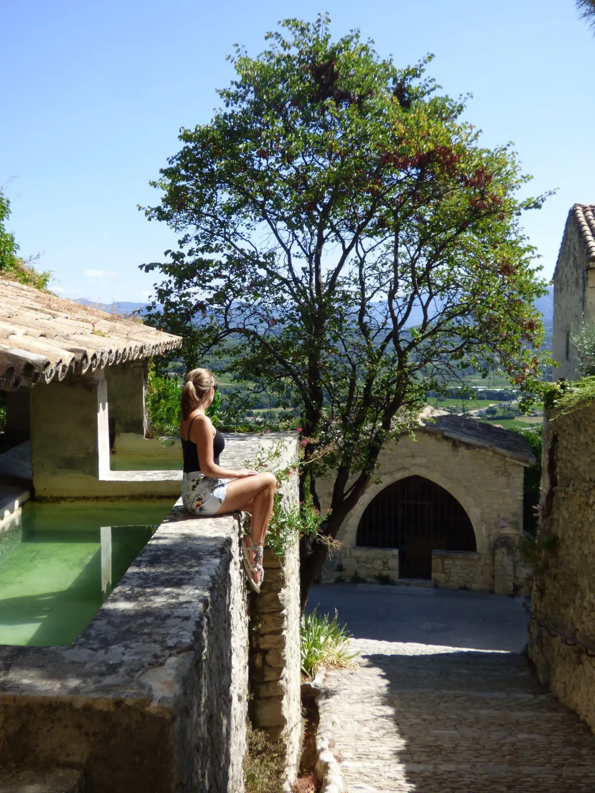 Woman sitting at the edge of the old washhouse, valley below