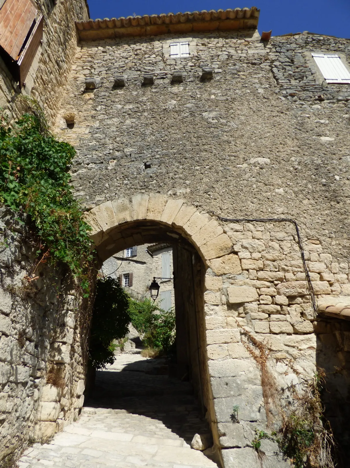 Vaulted passage beneath a house, lantern fixed to the stone