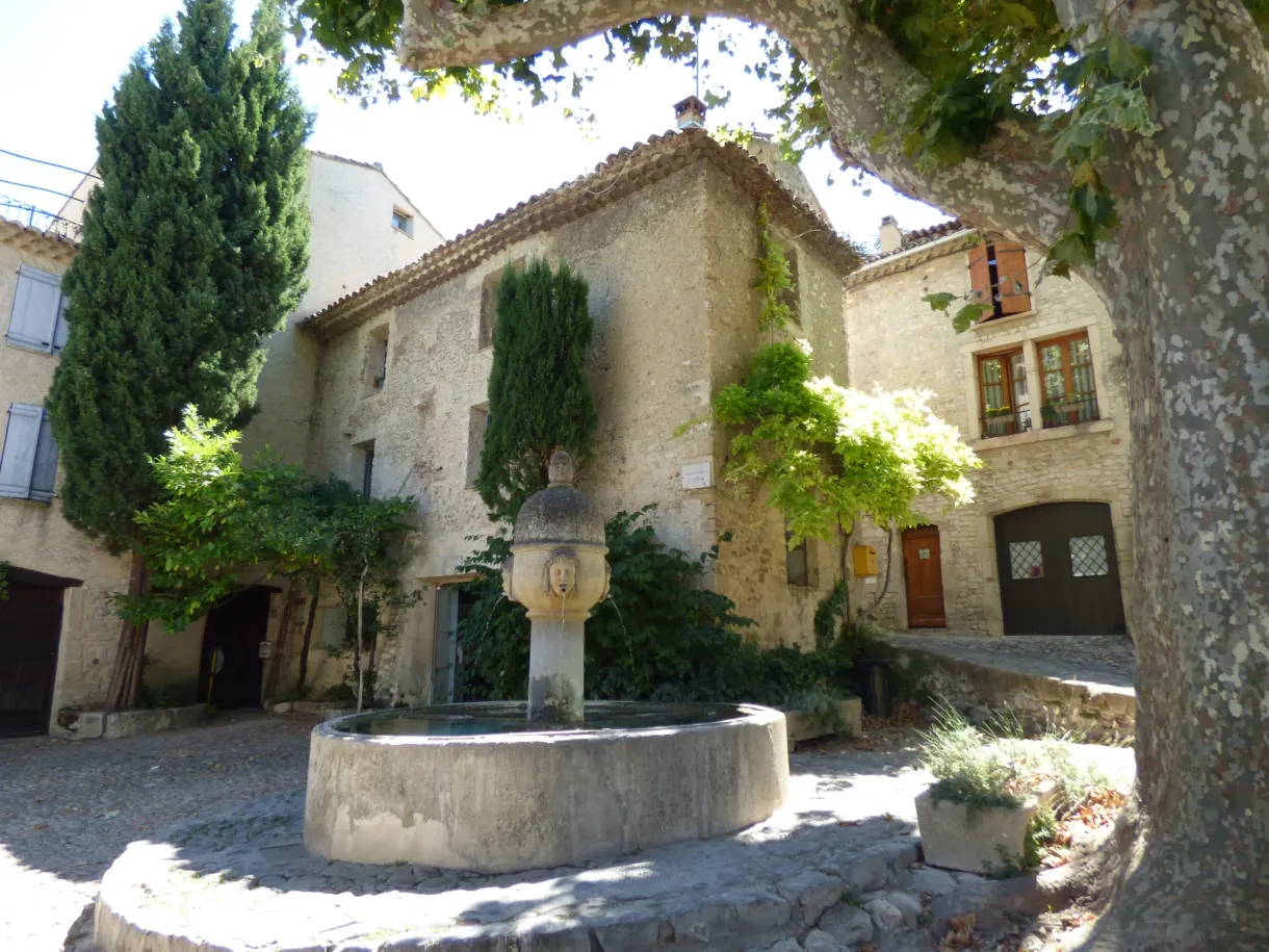 Circular stone fountain on a shaded little square