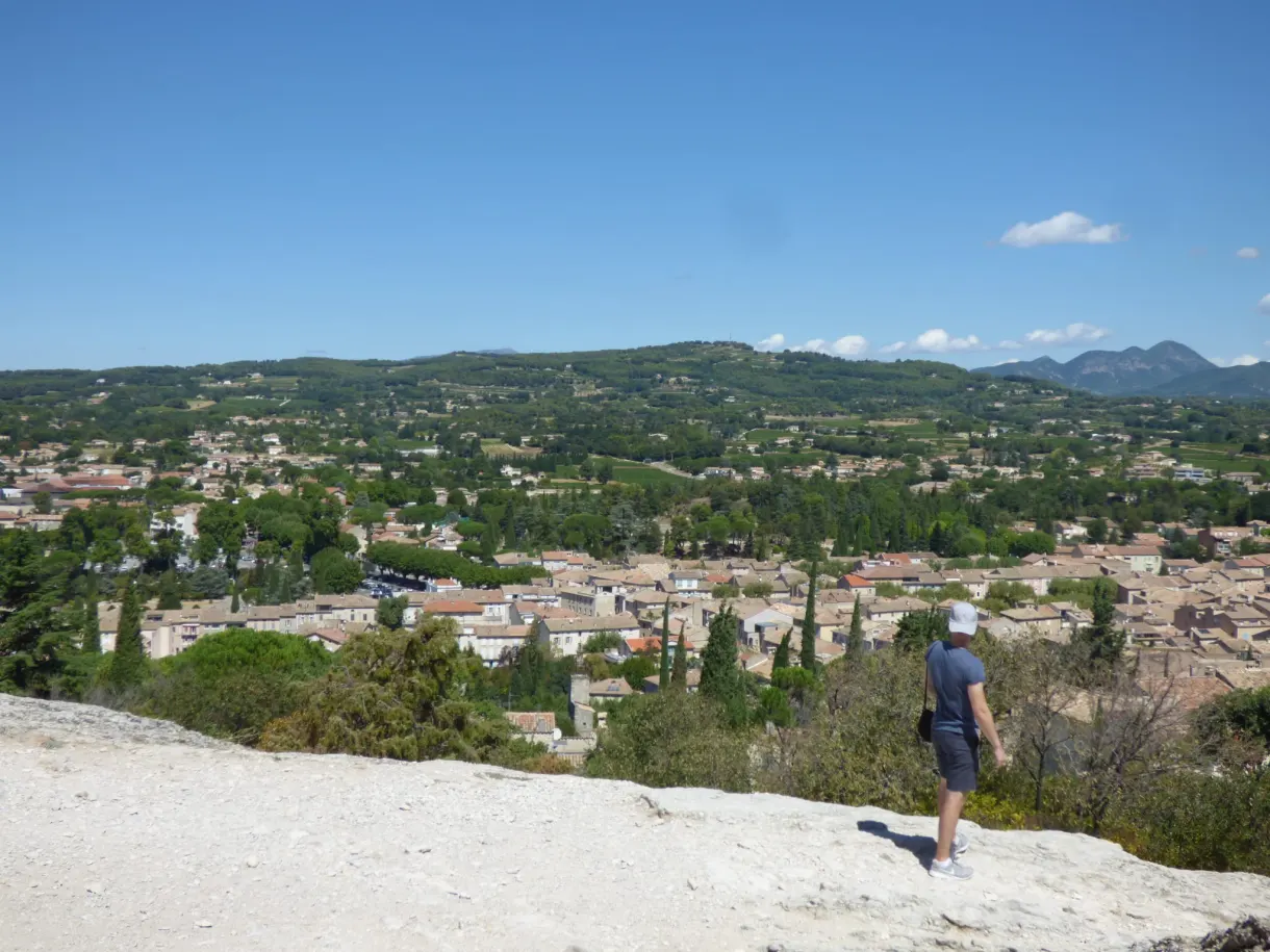 Walker on the rock slab overlooking the plain and the roofs