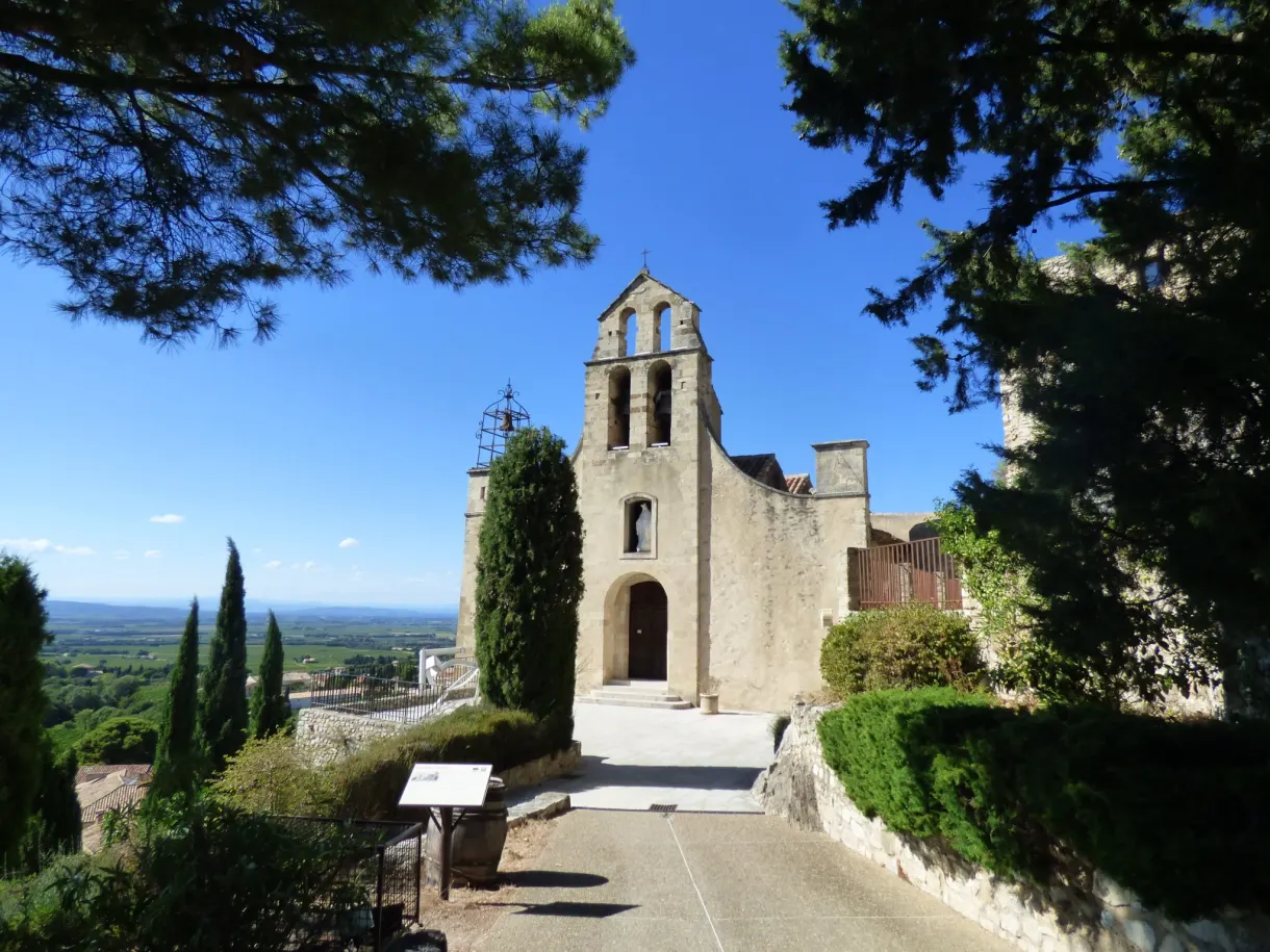 Church with a bell gable and cypresses overlooking the wine-growing plain