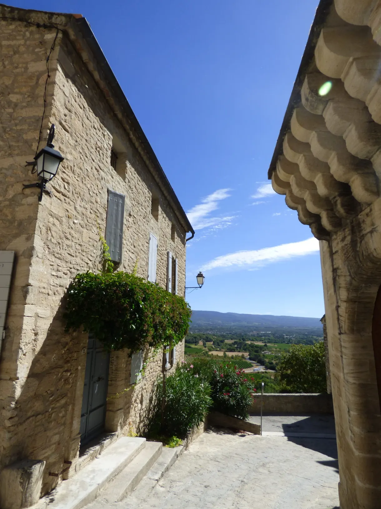 Tight alleyway, flower-decked balcony and a glimpse of the plain