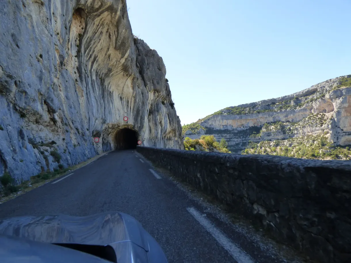 Entrance to a tunnel carved into the rock, seen from the road