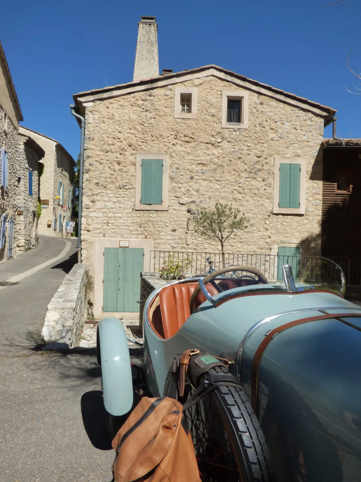 Blue vintage car parked in front of a stone house