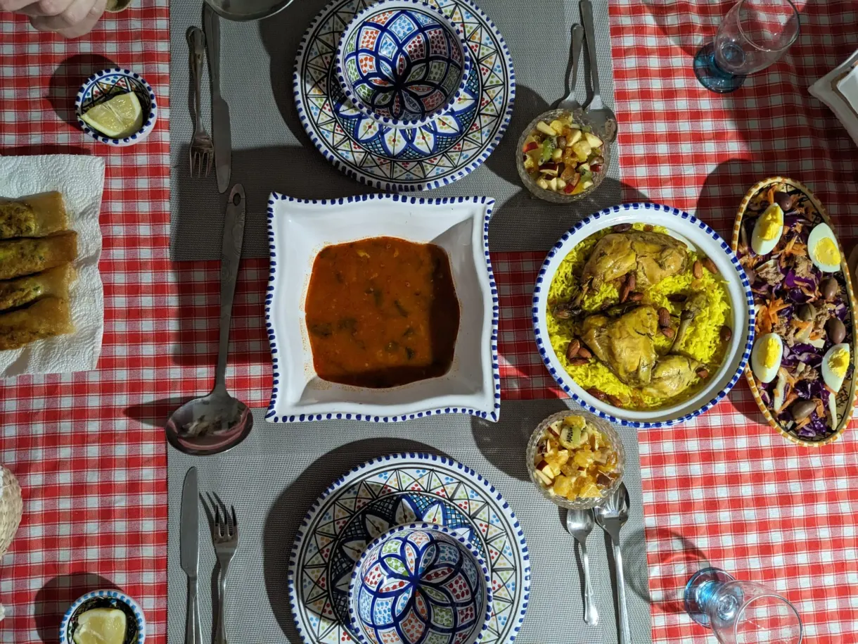 Repas tunisien vu du dessus : poulet au riz, sauce, salade et bricks dans de la vaisselle peinte